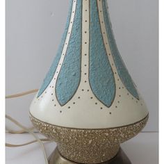 a blue and white vase sitting on top of a metal stand with a cord plugged into it