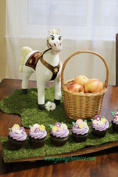 cupcakes are arranged in the shape of a horse and a basket of apples