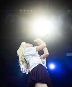 a woman in a white shirt and black skirt performing on stage