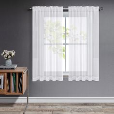 a room with a table, bookcase and window curtain in white sheer curtains on the windowsill