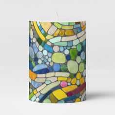 a candle that is made out of glass and has different colored stones on it,