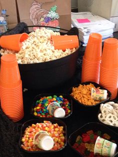 a table topped with bowls filled with candy corn and orange cups next to each other