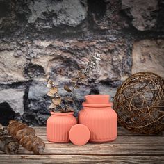 two orange vases sitting on top of a wooden table next to a ball and plant