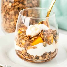 a glass filled with granola and yogurt on top of a white plate