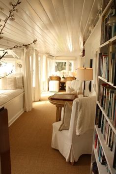 a living room filled with lots of furniture and bookshelves next to a window