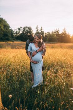 a pregnant woman hugging her husband in a field