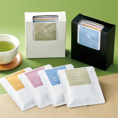 four tea bags sitting on top of a table next to a cup and saucer