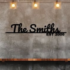 the smiths est 2006 sign is mounted on a concrete wall with lights above it