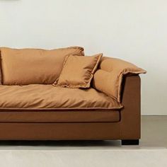 a brown couch sitting on top of a white floor next to a wall with a clock above it