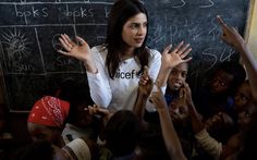 a woman standing in front of a blackboard surrounded by children