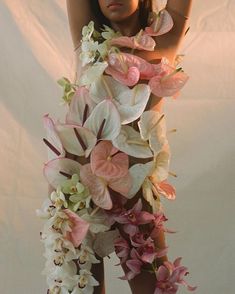 a woman is standing with her arms behind her head and flowers all around her body