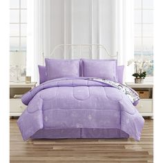 a bed with purple comforter and pillows in a room