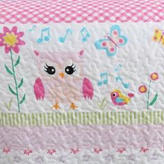 an owl quilt with musical notes and flowers on the front, sitting on a bed