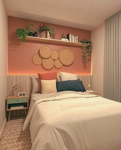 a bedroom with pink walls and white bedding, plants on the shelf above the bed