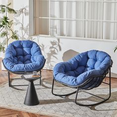 two chairs and a table on a rug in a room with wood flooring, one chair is blue and the other is black