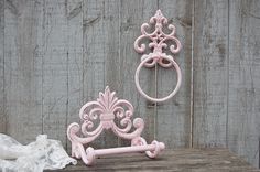 two pink cast iron towel racks on a wooden table next to a white ruffled cloth