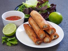 some food is on a white plate and next to a bowl of dipping sauces