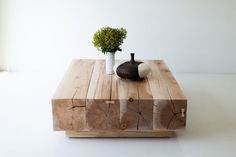 a wooden table topped with a vase filled with green plant sitting on top of it