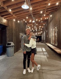 a man and woman are standing in an empty building with lights on the ceiling above them