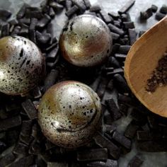 three metal balls and a wooden spoon on top of some black rocks with brown speckles