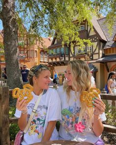 two women sitting on a bench eating pretzels