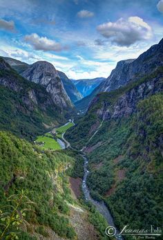 the valley is surrounded by lush green mountains and blue sky with white clouds in the background