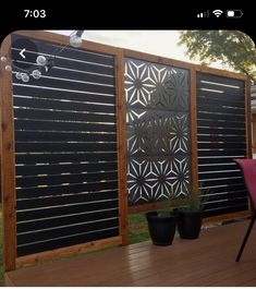 a wooden deck with two planters and a privacy screen on the side of it