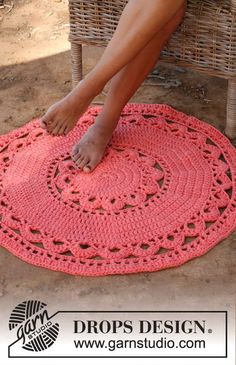 a woman is sitting on a wicker chair with her feet propped up on the pink crocheted rug