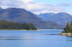 there is a boat in the water near some trees and mountains on the other side