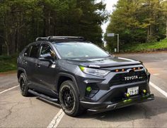 a gray toyota rav parked in a parking lot next to some trees and bushes