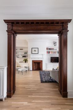 a living room filled with furniture and a fire place next to a doorway that leads into a dining room