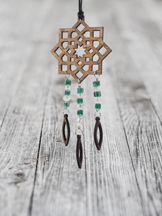 a wooden wind chime with green beads hanging from it's side on a string