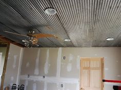 an unfinished room is being remodeled with paint and drywalling on the walls, ceiling fan in the foreground