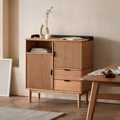 a wooden cabinet sitting on top of a hard wood floor next to a table and chair