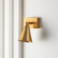 a gold wall light mounted on the side of a white wall next to a window