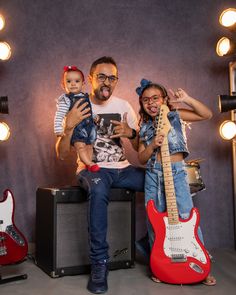 a man and woman are posing for a photo while holding two small children in front of guitars