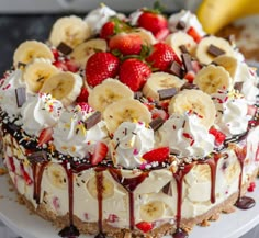 a cake with bananas, strawberries and whipped cream on top is sitting on a plate