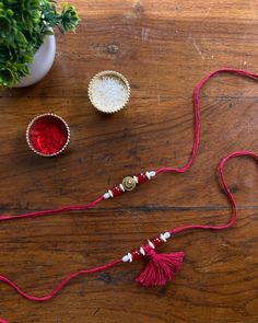 a red string with beads and other items on a wooden table next to a potted plant