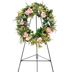 a wreath with pink roses and greenery on it is displayed in front of a white background