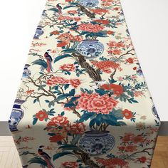 the table cloth is covered with flowers and birds in blue, red, orange and white