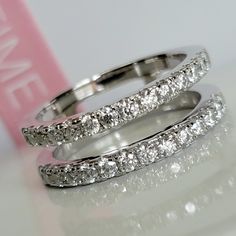 two white gold wedding rings with diamonds on top of each other and one diamond in the middle