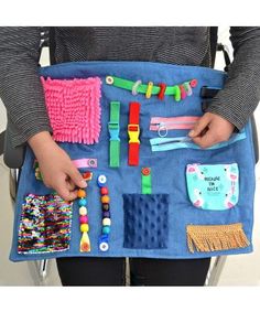 a woman holding a blue bag filled with lots of different items on top of it