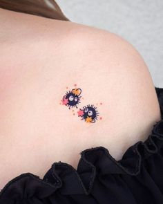 the back of a woman's shoulder with two small tattoos on it