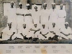 an old black and white photo of men in front of a wall with writing on it