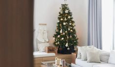 a living room with a christmas tree in the corner and other decorations on the table