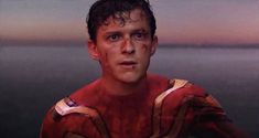 a young man in a red shirt is staring at the camera with blood all over his face