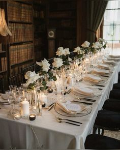 a long table is set up with white flowers and candles for an elegant wedding reception