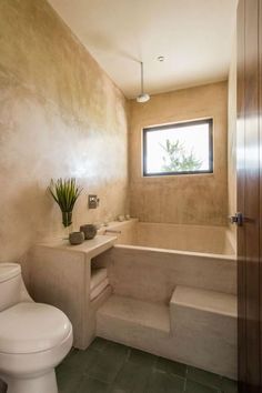 a bathroom with a toilet, sink and bathtub next to a window in the wall