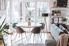 a living room filled with furniture and lots of windows next to a wall covered in plants