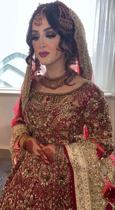 a woman in a red and gold bridal gown with her hands on her hips